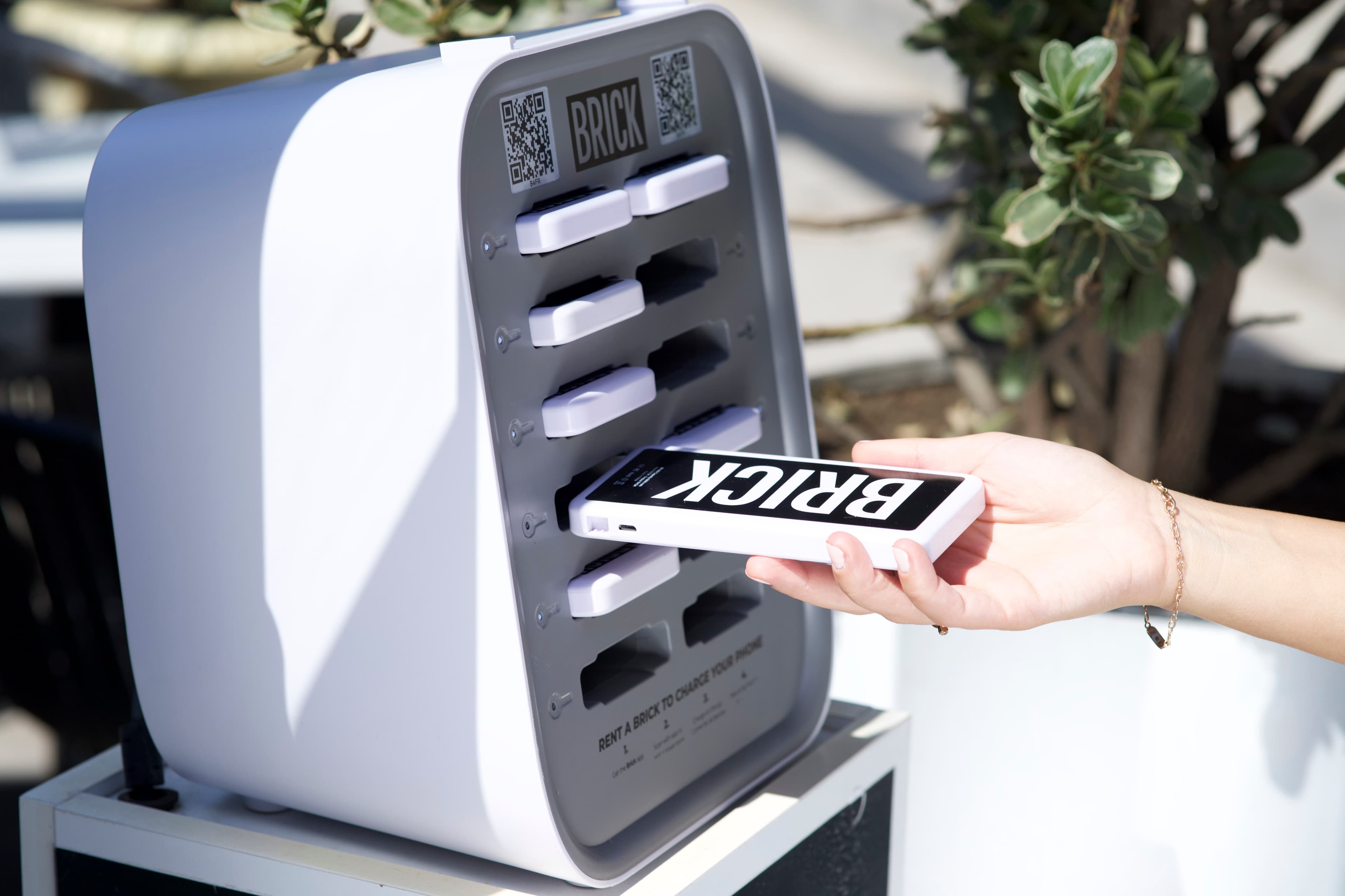 Eine Hand, die eine Brick-Powerbank in eine Station einführt